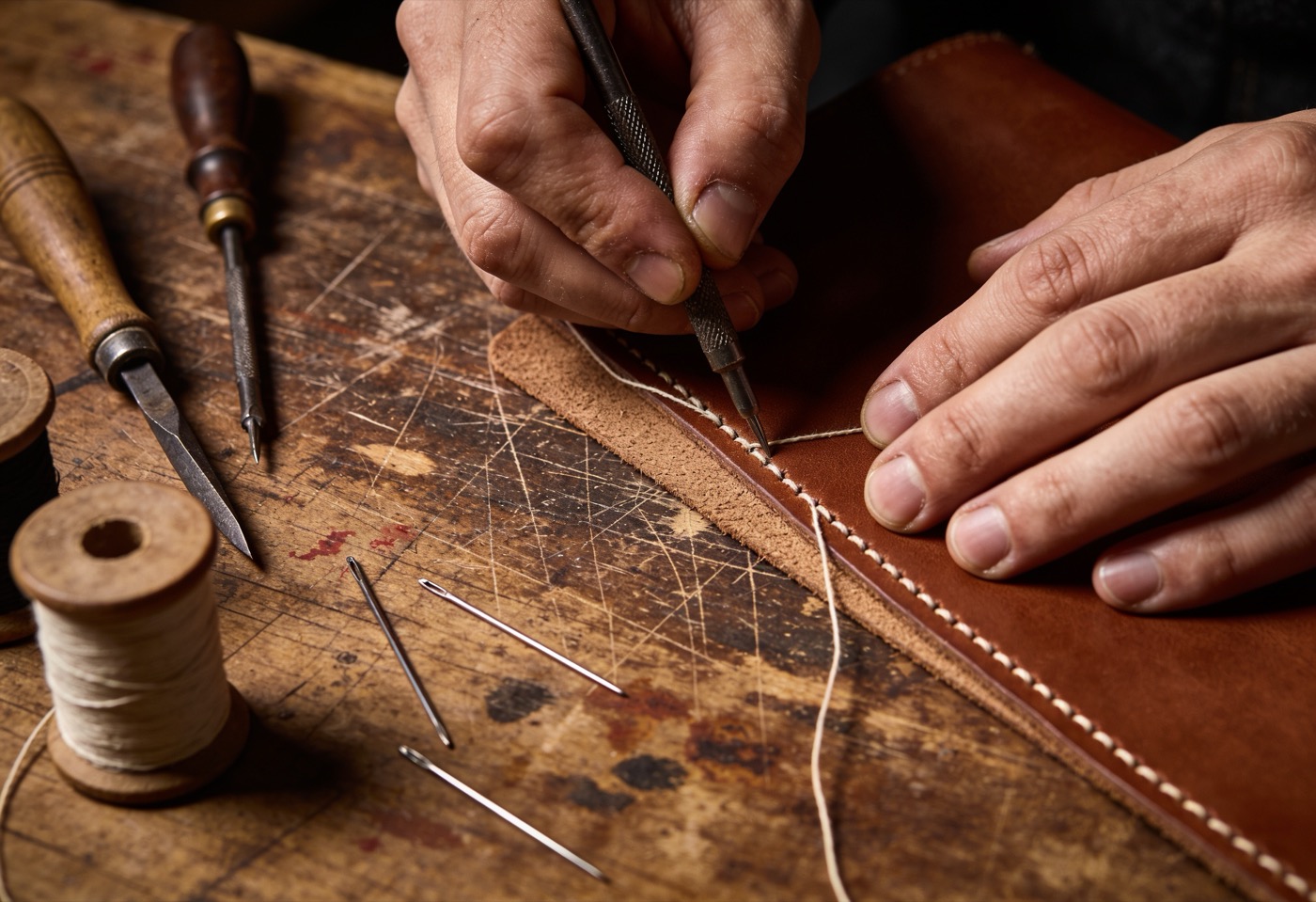 Hand-stitching at the bench — judgement no machine can be taught.